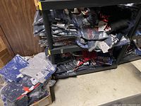 Shelving unit with stacks of plastic-wrapped Majestic women’s MLB tops showing assorted teams and colors