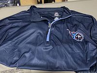Close-up of navy quarter-zip pullover shirt with Tennessee Titans logo showing fabric texture and zipper detail.