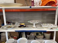 Overview of five porcelain pieces on shelf: parrot plate, Aynsley cup and saucer, pedestal compote, scalloped bowl