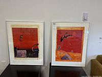 Two framed abstract collages side by side on a table