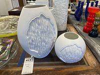 Front view showing two white porcelain vases with a textured abstract relief pattern on the front