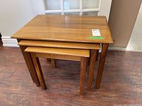Set of three wooden nesting tables stacked inside each other on hardwood floor