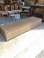 Side view of the closed wicker lounger showing its rectangular shape and woven texture