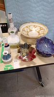 Overall display of seven ceramic pieces including bowls and vases on beige table