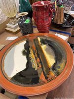 Large round platter with abstract black, burnt orange, and beige glaze on an orange rim
