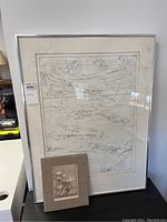 Framed Diane Pugen etching with smaller unframed Margaret Thomas print resting against it