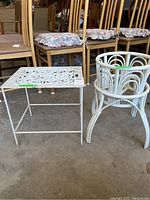 Photo showing white metal side table with floral cutout design next to wooden circular plant stand
