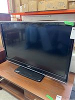 Front view of Toshiba 46 inch Regza TV showing the screen and stand on a wooden shelf.