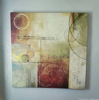 Square abstract canvas painting hung on a wall showing geometric forms with circles and rectangles in cream, burgundy, yellow, and green tones.