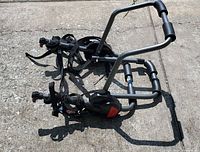 Metal bike rack for two bicycles shown on concrete surface with visible straps and padding.