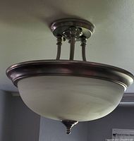 Ceiling light fixture with sterling steel finish and frosted glass dome shade from different angles.