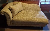 Golden tan chaise lounge sofa with floral damask fabric and matching pillow, shown from angled views.