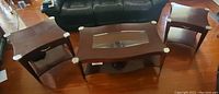 Set of three coffee tables on wood floor with black couch in background