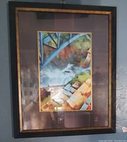 Photo of one framed picture showing colorful abstract landscape with black and gold frame and brown mat.