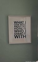 Framed picture featuring an inspirational quote about home and love against a gray wall background.
