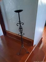 Full view of the 32 inch iron candle holder showing its tripod base and scroll design in the center