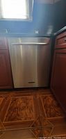 Front view of stainless steel KitchenAid built-in dishwasher between cabinetry
