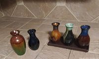Photo showing 5 small colorful glazed vases and one small wooden tray containing 4 of the vases