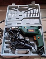 Green Nokina corded drill in gray carrying case with drill bits and accessories.