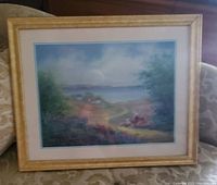 Photo of the framed landscape painting showing countryside scene with path, trees, and water.