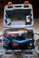 Photo of Ryobi 13 Amp circular saw inside gray hard plastic carrying case with orange latches.