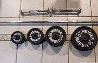 Photo shows Weider branded weight plates from 2 lbs to 25 lbs, two short dumbbell bars with collars, and one 7ft barbell bar all laid on tiled floor.