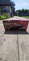 Photo of Master Lock Steering Wheel Lock box outdoors on pavement with brand and product name visible