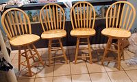 Four wooden bar stools lined up, showing the front and side views, highlighting the design and finish.