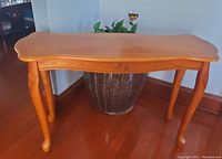 Front view showing full table structure, curves of tabletop, and carved leg details.