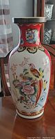 Full view of the tall ceramic vase displaying colorful birds and floral hand-painted decorations