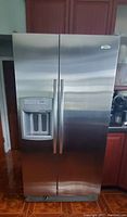 Front view of stainless steel side-by-side Whirlpool refrigerator showing external ice and water dispenser