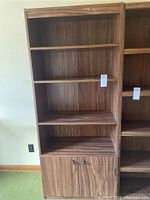 Front view of wood veneer bookshelf showing four fixed shelves and lower 2-door cabinet, natural wood grain finish.