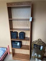 Front view of the tall veneer bookshelf with 4 shelves and backing, showing wood grain finish and some contents on one shelf.
