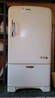 Front view of vintage McClary refrigerator showing closed main door, pull-out drawer at bottom, and original metal handle.