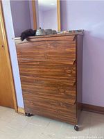 Front view of the 4-drawer wooden dresser showing wood grain finish and casters at bottom.