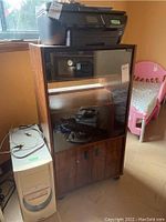 Photo showing HP Officejet 5740 printer placed atop a wooden cabinet next to a pink child's bed, with LG computer tower on the floor to the left of the cabinet.