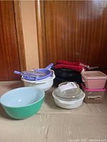 Photo showing green Pyrex mixing bowl, Tupperware containers, colanders, casserole dishes, and red oven mitts.