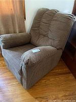 Side angled view of the brown corduroy recliner chair showing padded armrest and cushioned backrest.