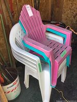 Stacked pair of children's resin lawn chairs in pink and teal colors with Adirondack style slatted design, highlighting the size difference from adult chairs.