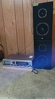 Stereo receiver with tape deck and tuner model 5425 shown on carpet with pair of vertical black speakers nearby.