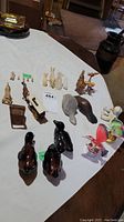 Top-down photo of various small animal figurines arranged on a table, including dark glass ducks, wood and stone animals, and a small chair figurine.