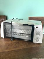 Front angle view of the White-Westinghouse toaster oven showing the control knobs, power cord, and door with a wire rack visible inside.