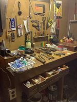 Full view of wooden workbench, pegboard and assorted tools hung and placed on top