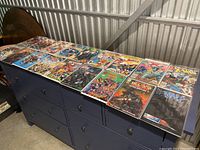 Full view of 15 comic books laid out on a blue dresser, each in protective sleeves, featuring various themes and characters.