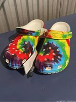 Front angled view of the Crocs clogs showing tie-dye colors and ventilation holes.