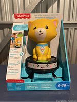 Front angle of Fisher-Price Crawl After Cat toy in original packaging, showing the yellow cat figure on black base with colorful numbers and buttons.