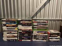 Photo of stacked video game cases for Xbox, Xbox 360, and PlayStation 2 showing fronts and spines of cases in good condition without discs.