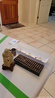 Photo showing all three items: the small carved figurine, the metal abacus on a marble-like base, and the ceramic chopstick rest plate.