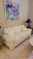 Cream color Nancy Rich couch with three removable cushions, light striped pattern, and rounded armrests.