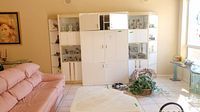 Full view of the five-piece white entertainment center with central, side, and corner cabinets in living room setting.